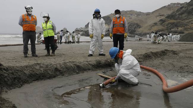 LIMA, PERU - JANUARY 20: Cleaning teams work to remove oil at the shores after an oil spill in the Ventanilla Sea in the province of Callao has stained the beaches of the district area in Lima, Peru on January 20, 2022. The spill was recorded on Saturday, January 15, during the unloading of crude oil from a ship at the La Pampilla Refinery, after strong waves reached the Peruvian coast as a result of the underwater volcanic eruption near Tonga. On January 20, the district of Ventanilla asks the government to declare an environmental emergency after the oil spill, in addition to groups of people and animalists who came to the rescue of various types of birds. (Photo by Klebher Vasquez/Anadolu Agency via Getty Images)