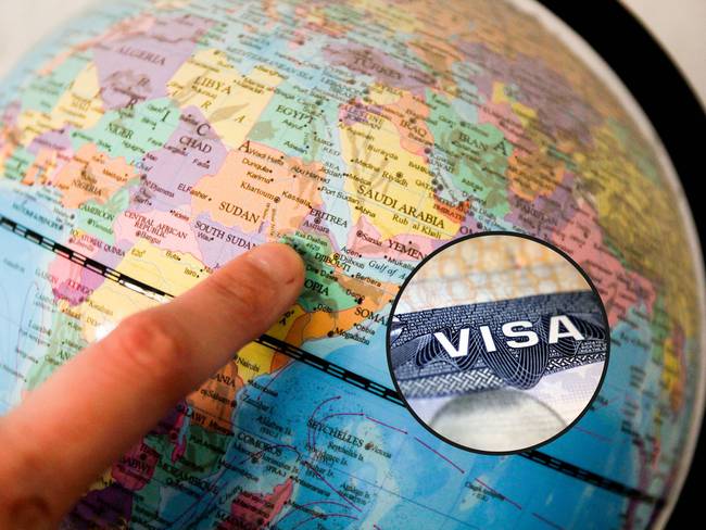 De fondo, una persona señalando un país en un globo terráqueo. En el círculo, la imagen de la visa de turista para viajar a Estados Unidos / Fotos: GettyImages