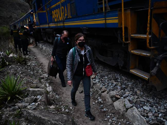 Los turistas varados que visitaban la ciudadela inca de Machu Picchu caminan junto a las vías del tren después de ser evacuados en tren a Ollantaytambo, Perú, el 17 de diciembre de 2022.