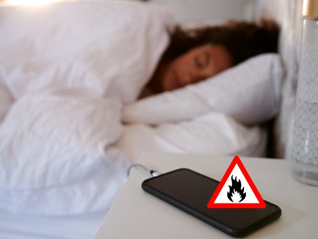 Celular cargando en la mesita de noche, mientras una mujer duerme al lado (Getty Images)