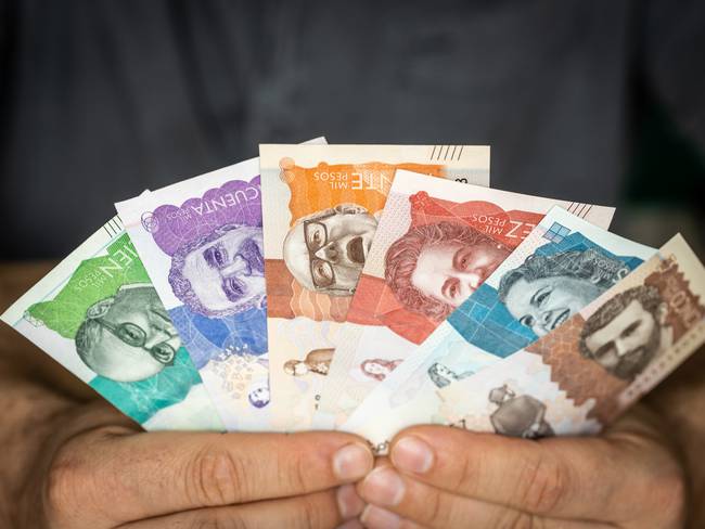 Hombre sosteniendo billetes colombianos de diferentes denominaciones (Getty Images)