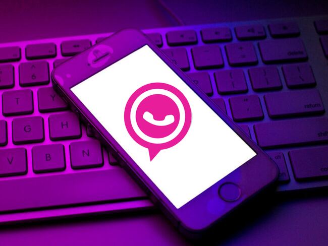 Celular iPhone con el logo de WhatsApp rosado en su pantalla, sobre un teclado de computador (Getty Images)