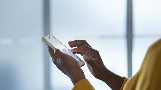 Close-up of businesswomans hands holding phone, in conference room
