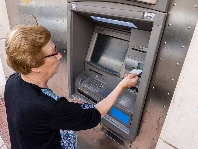 Mujer anciana retirando dinero de un cajero electrónico (Foto vía Getty Images)