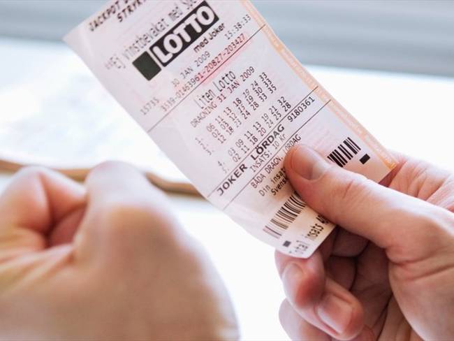 Foto ilustrativa de una persona con un billete de lotería. Foto: Getty Images/Maskot
