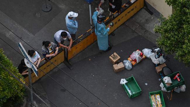 A resident collects food from a delivery worker at a checkpoint on a street during a Covid-19 coronavirus lockdown in the Jing&#039;an district in Shanghai on May 17, 2022. (Photo by Hector RETAMAL / AFP) (Photo by HECTOR RETAMAL/AFP via Getty Images)