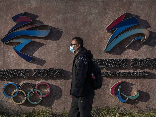 BEIJING, CHINA - DECEMBER 07: A visitor walks by the logos for the Beijing 2022 Winter Olympics and Paralympics at Shougang, a former power plant which now also houses the headquarters of the Beijing Organizing Committee of the Olympic Games, on December 7, 2021 in Beijing, China. The games are set to open on February 4, 2022.(Photo by Kevin Frayer/Getty Images)