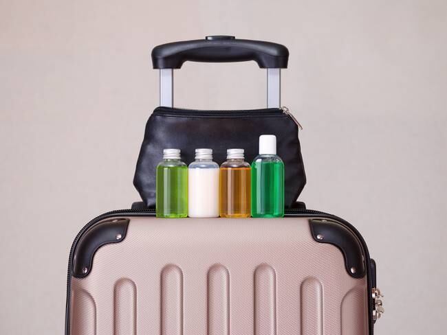 Maleta de viaje con botellas de productos y una cosmetiquera (Getty Images)