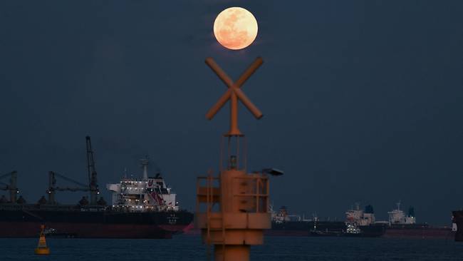 The full moon rises as the June 2022 &quot;Strawberry Supermoon&quot; in Singapore on June 14, 2022. (Photo by ROSLAN RAHMAN / AFP)