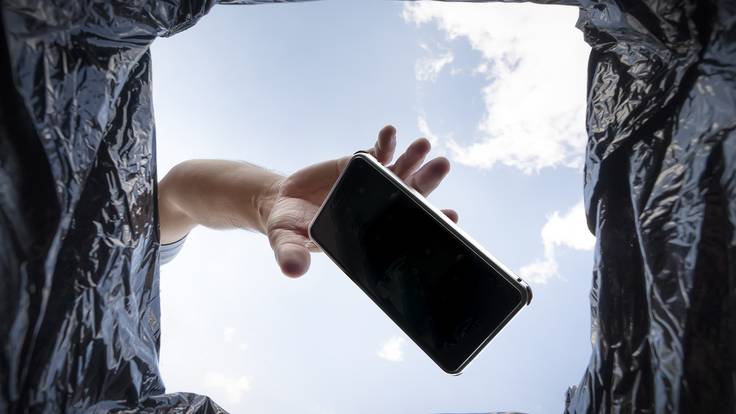 Hombre arrojando su celular a un basurero porque  no funciona / Foto: GettyImages