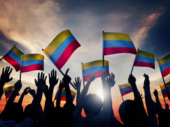 Personas alzando la bandera de Colombia (Foto vía Getty Images)