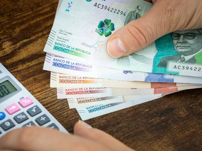 Persona contando billetes colombianos (Vía Getty Images)