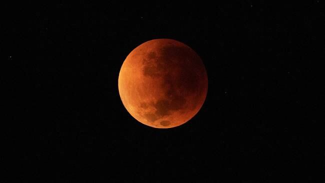 The blood moon is seen during a total lunar eclipse in Rio de Janeiro on May 16, 2022. (Photo by CARL DE SOUZA / AFP)