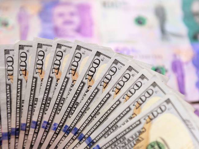 Dinero colombiano y dólares, imagen de referencia. (Photo by DANIEL MUNOZ/AFP via Getty Images)