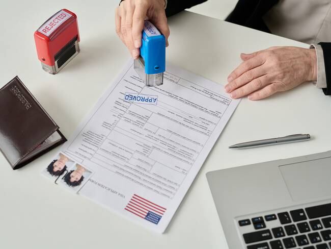 Hombre aprobando una solicitud de visa de un extranjero para entrar a Estados Unidos (Getty Images)