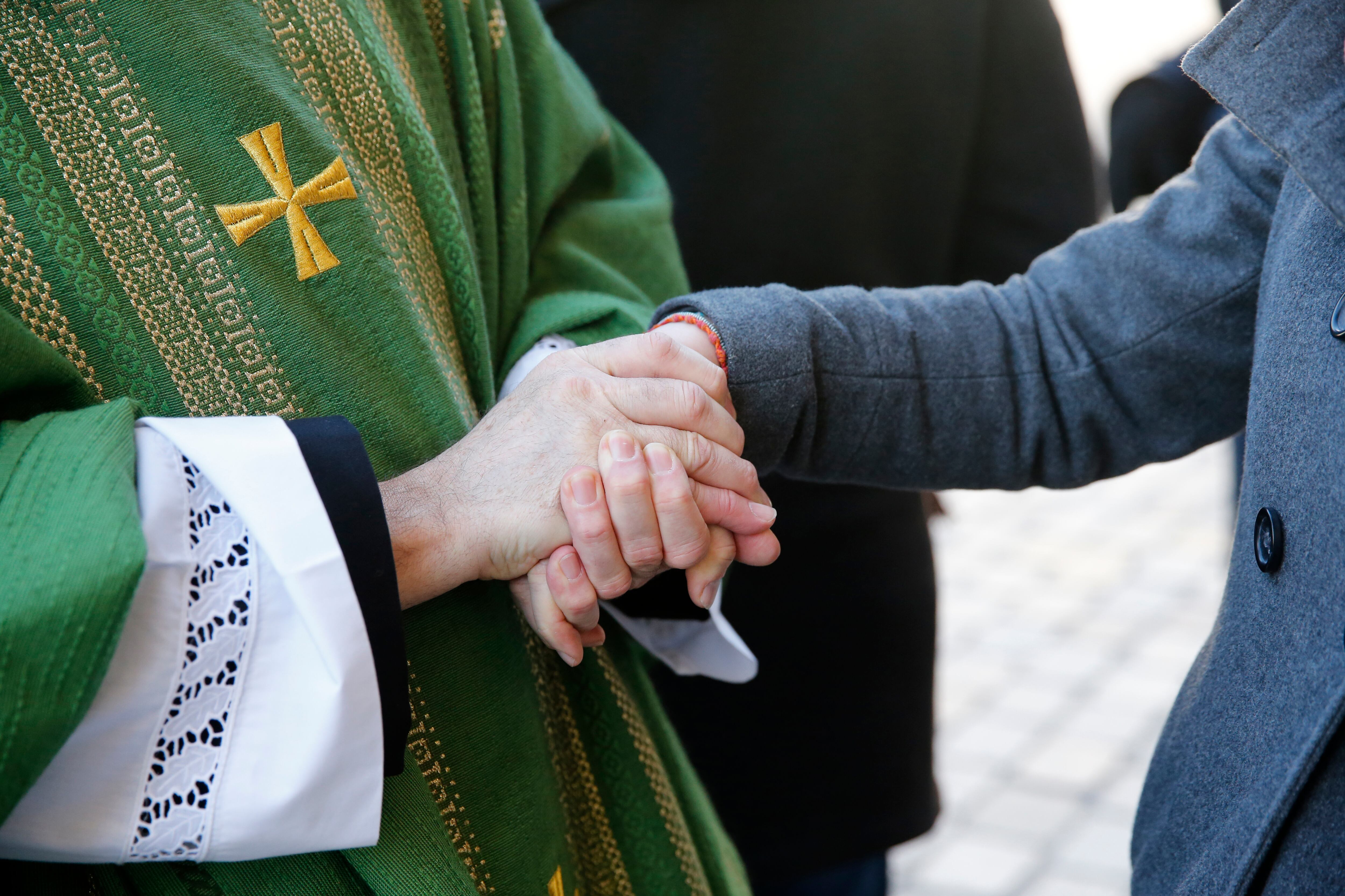 Catholic priest greeting parishioners after Mass.