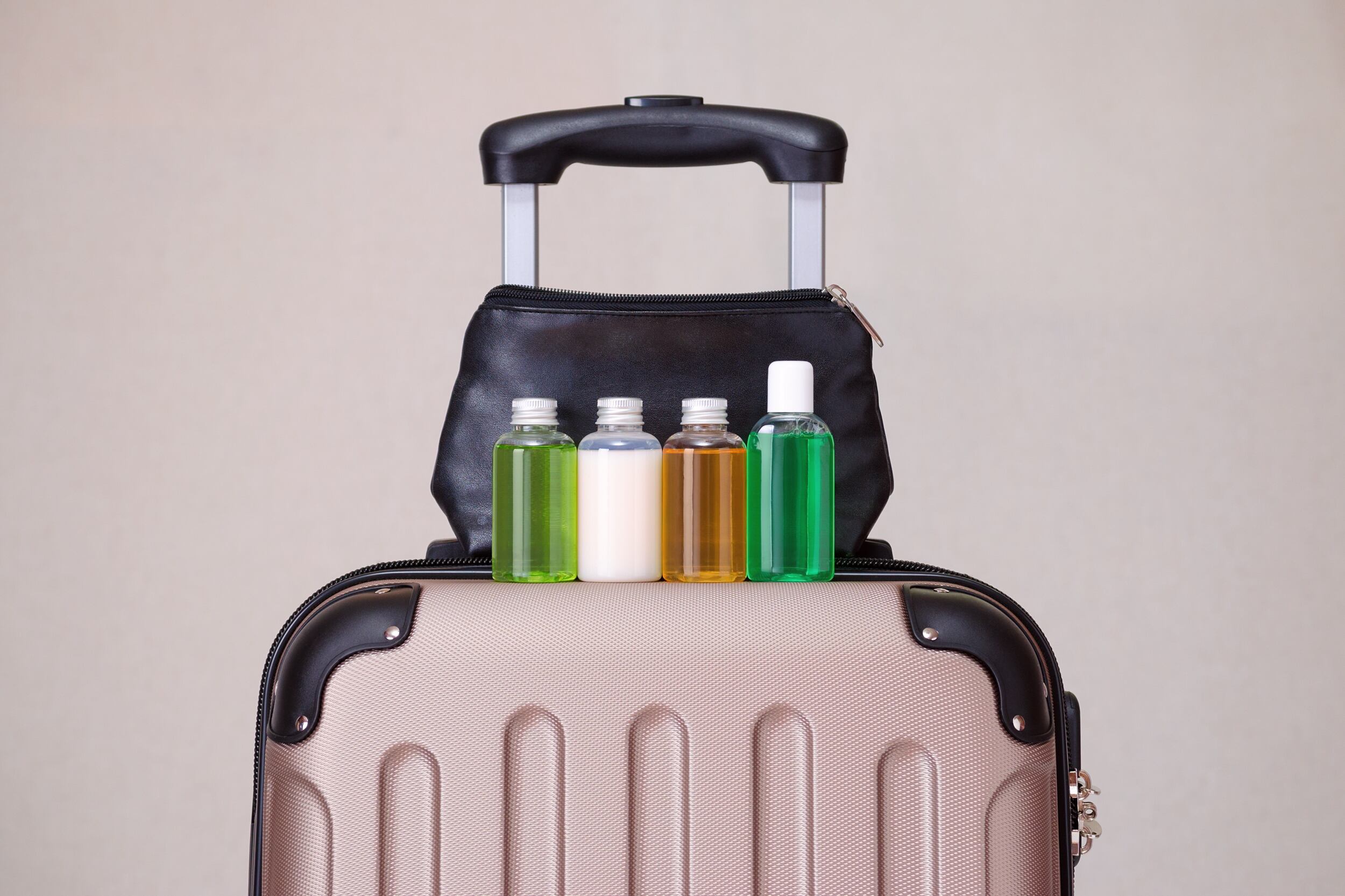 Maleta de viaje con botellas de productos y una cosmetiquera (Getty Images)