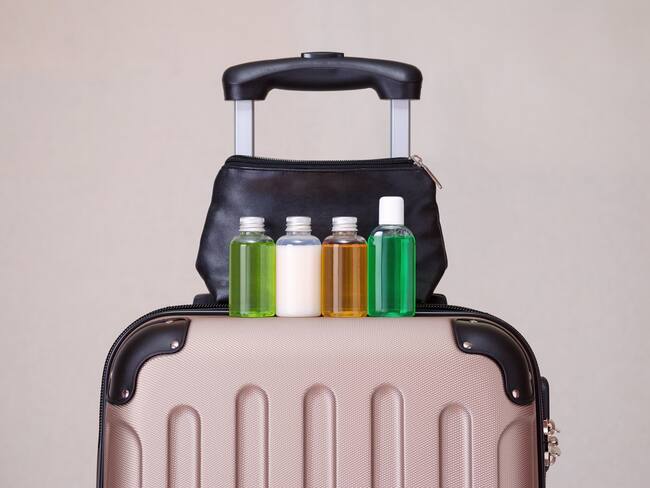 Maleta de viaje con botellas de productos y una cosmetiquera (Getty Images)