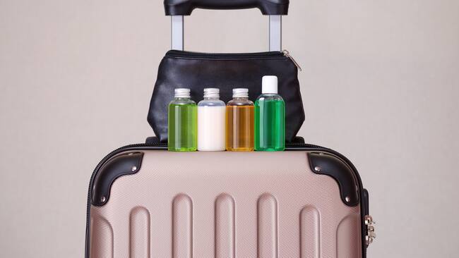 Maleta de viaje con botellas de productos y una cosmetiquera (Getty Images)