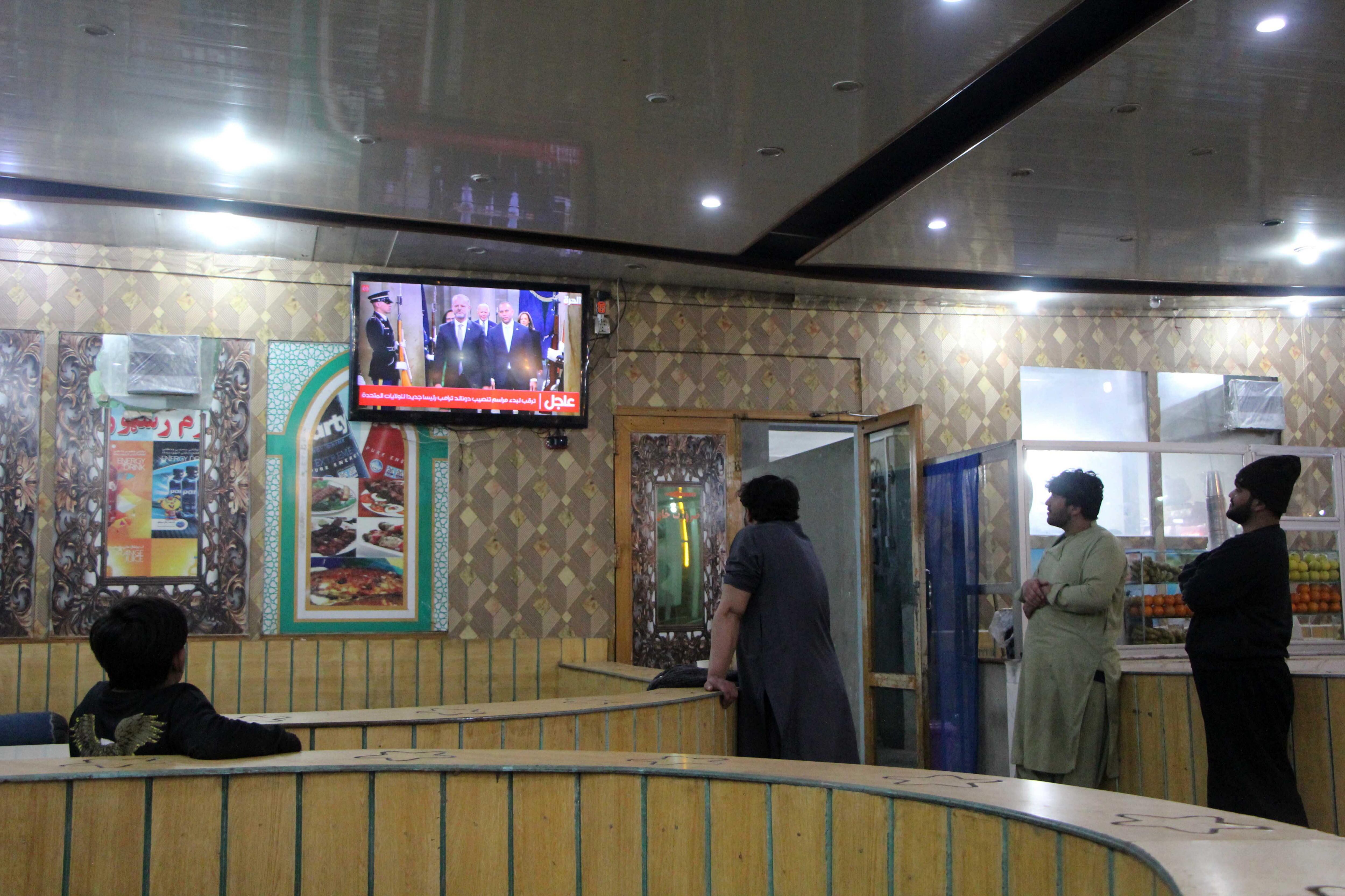 Kandahar (Afganistán), 21/01/2025.- Afganos observan en un televisor la ceremonia de investidura del presidente electo de Estados Unidos, Donald Trump.