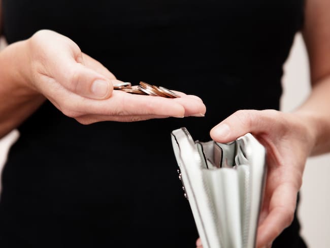 Woman with coins in hand with white leather purse