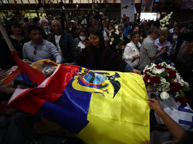 AME9921. QUITO (ECUADOR), 11/08/2023.- Simpatizantes colocan una bandera nacional sobre el féretro del candidato Fernando Villavicencio, durante un velatorio público en el Centro de Exposiciones hoy, en Quito (Ecuador). El féretro de Villavicencio, el candidato a la Presidencia de Ecuador asesinado el miércoles, salió del cementerio al que había sido trasladado para tener un breve velatorio público antes de regresar al camposanto y proceder con su inhumación. Los simpatizantes tuvieron la oportunidad de dar el último adiós a Villavicencio después de que llegaran hasta los exteriores del tanatorio y luego del cementerio para insistir en que se celebrara un velatorio público. EFE/ José Jácome
