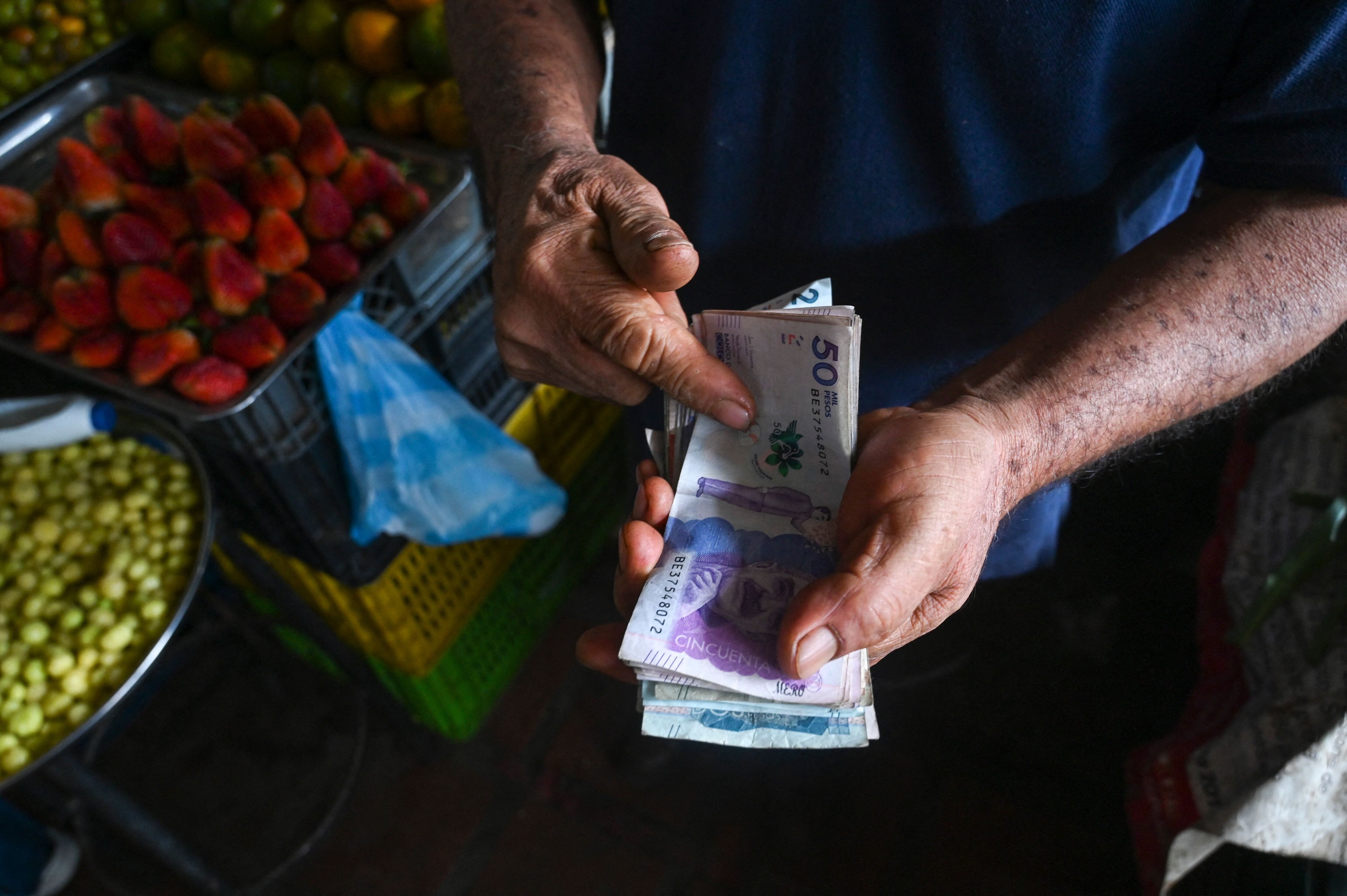 Un vendedor cuenta billetes de pesos colombianos en un mercado de Cali, Colombia, el 5 de enero de 2022. AFP vía Getty Images