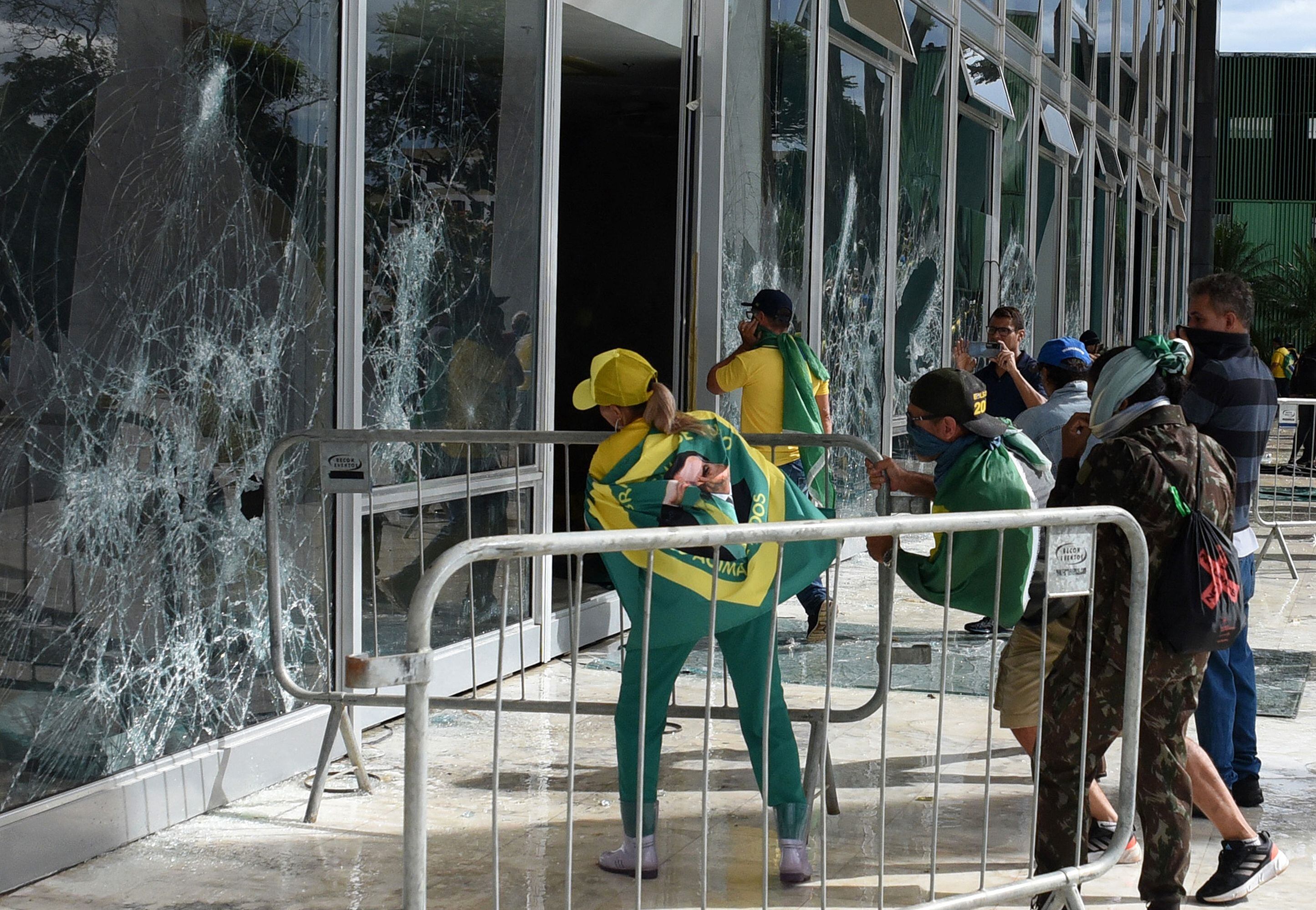Partidarios del expresidente brasileño Jair Bolsonaro destruyen una ventana del pleno de la Corte Suprema en Brasilia el 8 de enero de 2023. Foto de TON MOLINA/AFP vía Getty Images.