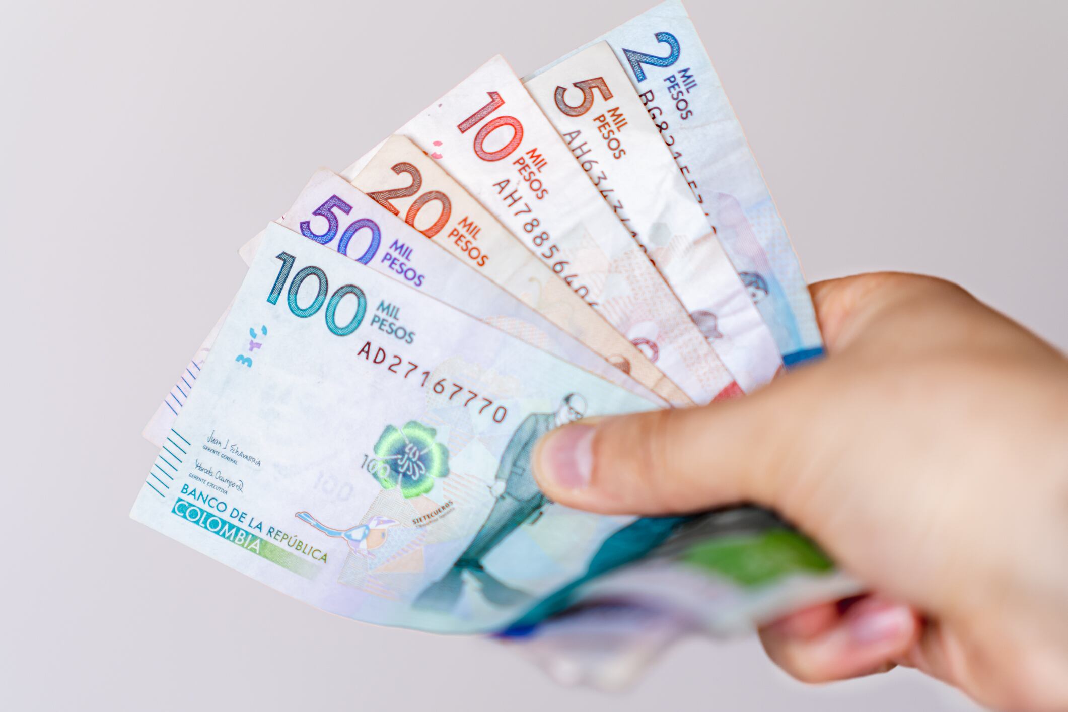Persona sosteniendo varios billetes colombianos (Getty Images)