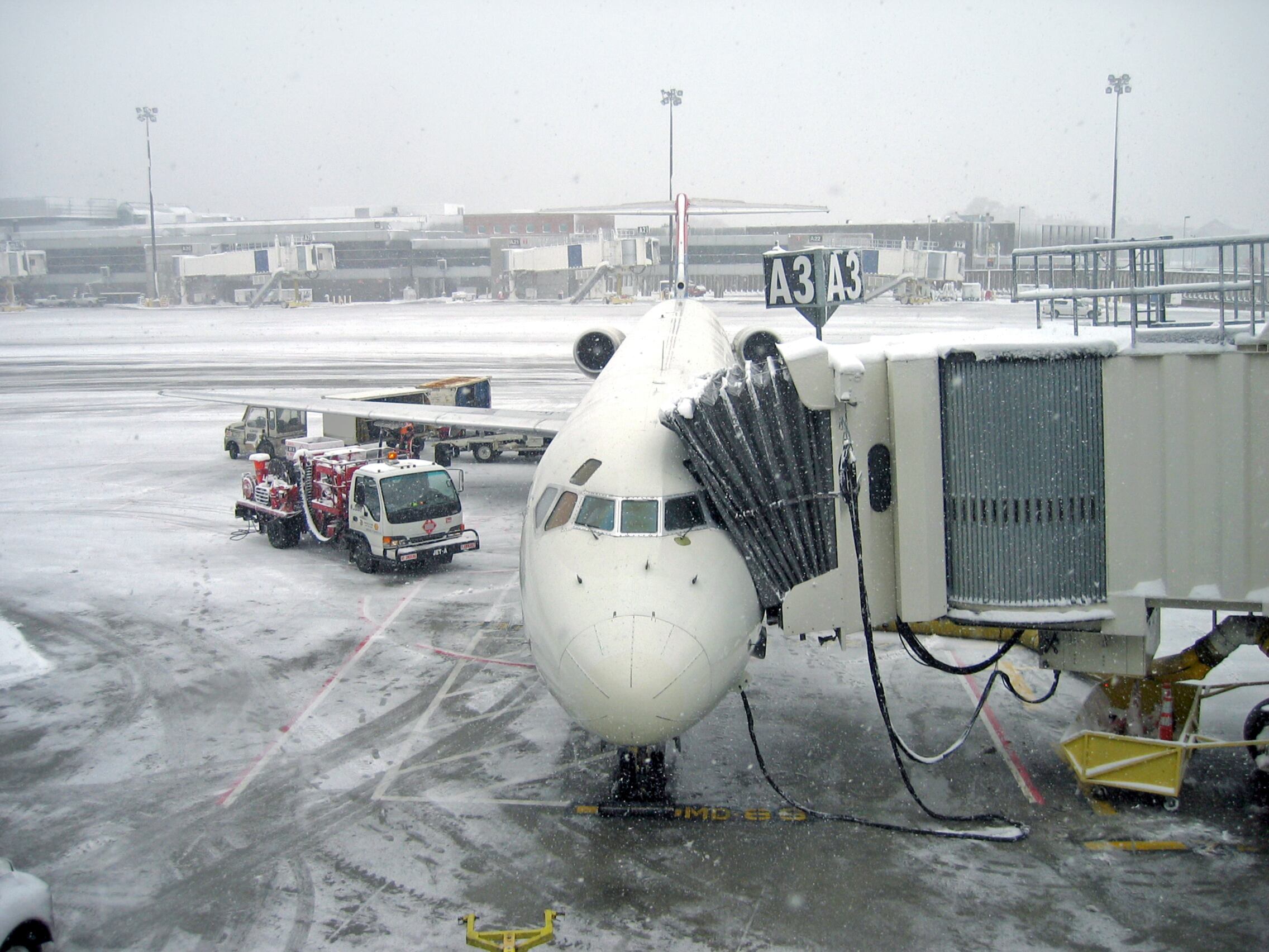 Aircraft at airport terminal during snowstorm, Logan Airport, Boston, Massachusetts, USA.