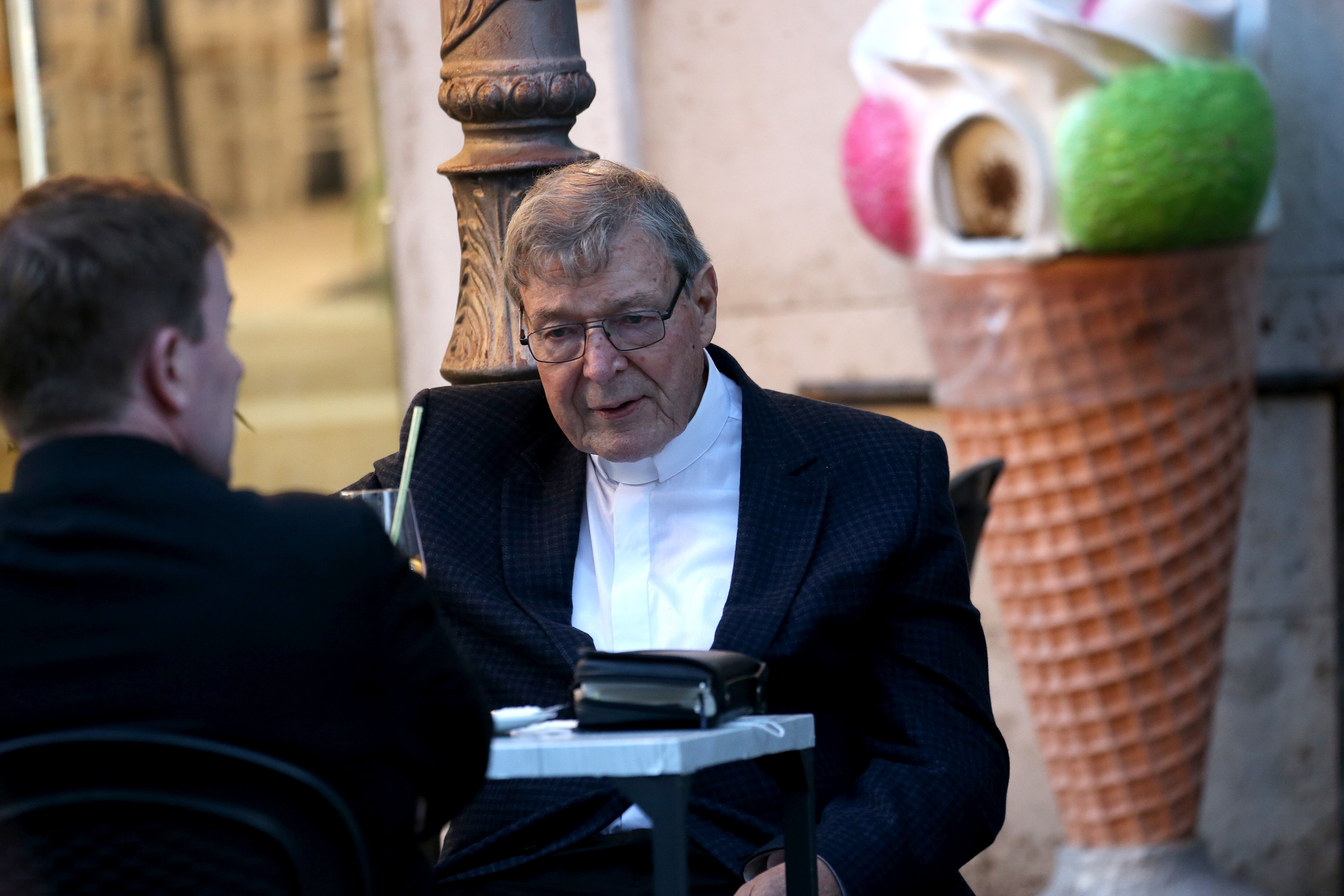 El ex arzobispo de Sidney, el cardenal australiano George Pell, se sienta con un joven sacerdote en un bar cerca de la Plaza de San Pedro el 4 de octubre de 2020 en la Ciudad del Vaticano, Vaticano. El cardenal Pell llegó de Sídney a Roma el 30 de septiembre de 2020. Foto de Franco Origlia/Getty Images.