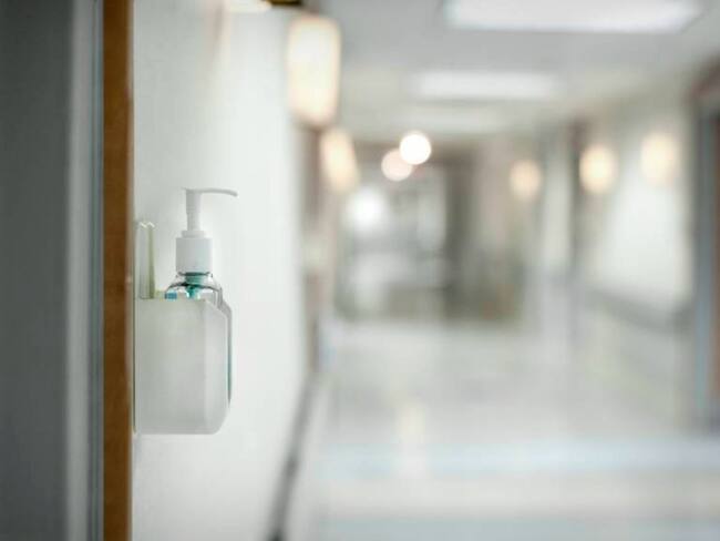 Hand sanitizer dispenser on wall of hospital in hallway / David Sacks