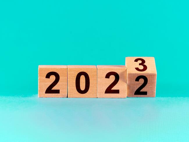Concept of the end of 2022 and the new beginning in 2023. Change from 2022 to 2023 in wooden cubes on a green background.