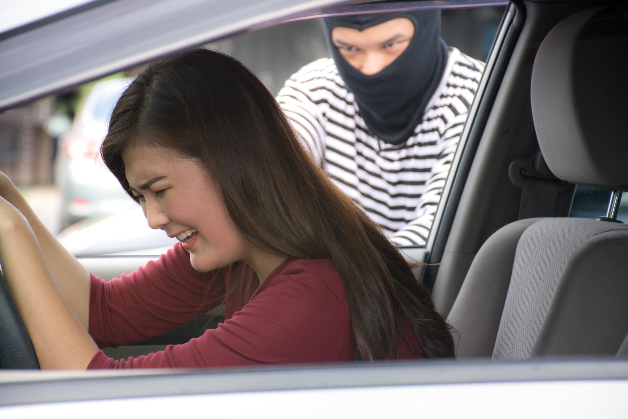Robber holding a gun for robbery car owner /Screaming Asian woman /Criminal and car thief concept