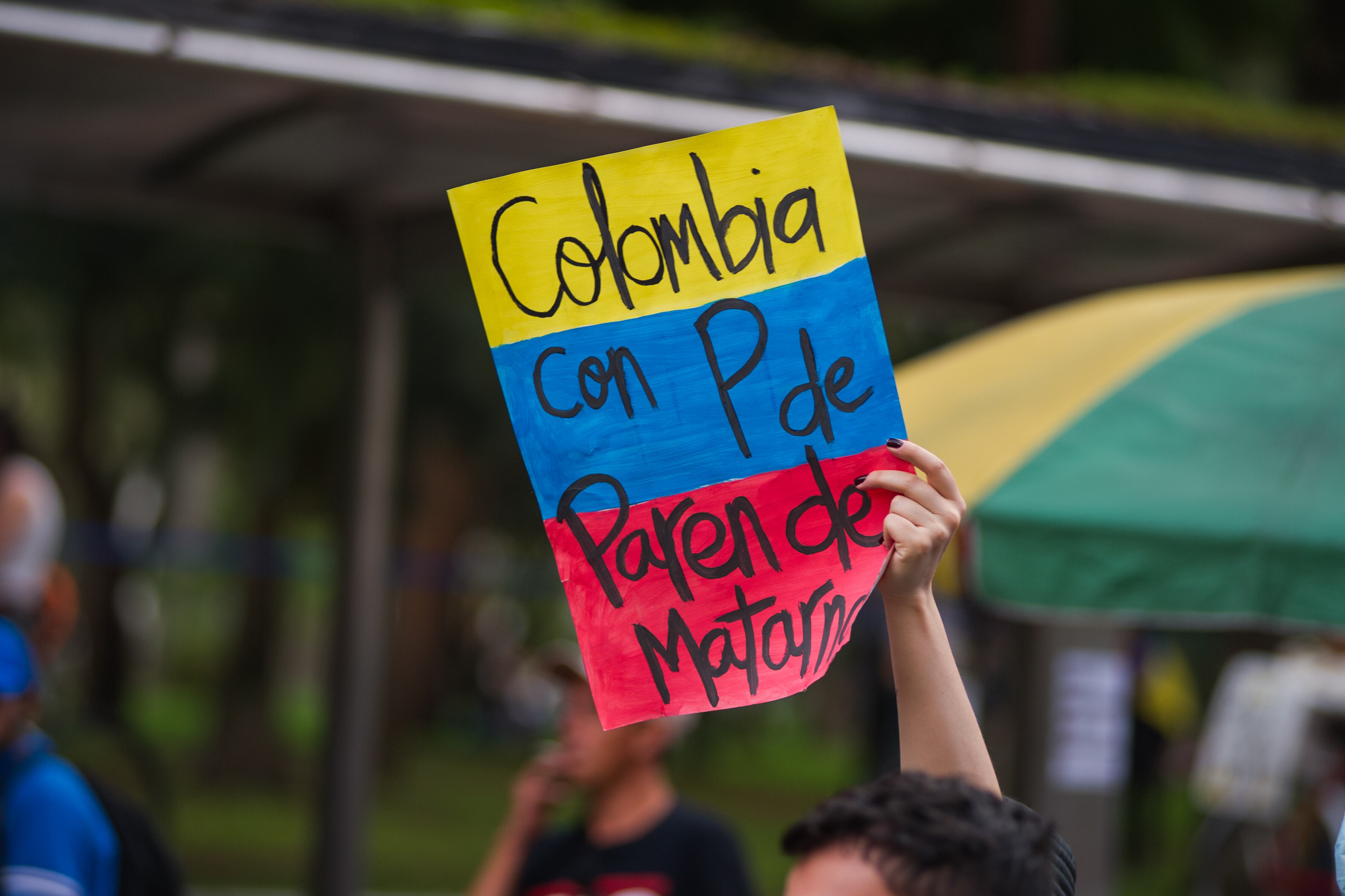 A demonstrator holds a sign with the colombian flag that reads 'Colombia with P of stop killing us' in Bogota, Colombia on May 7 2021 after peaceful demonstrators against the tax and health reform of president Ivan Duque and the killings of over 30 in hands of police brutality cases as demonstrations took main avenues of Bogota. (Photo by: Sebastian Barros/Long Visual Press/Universal Images Group via Getty Images)