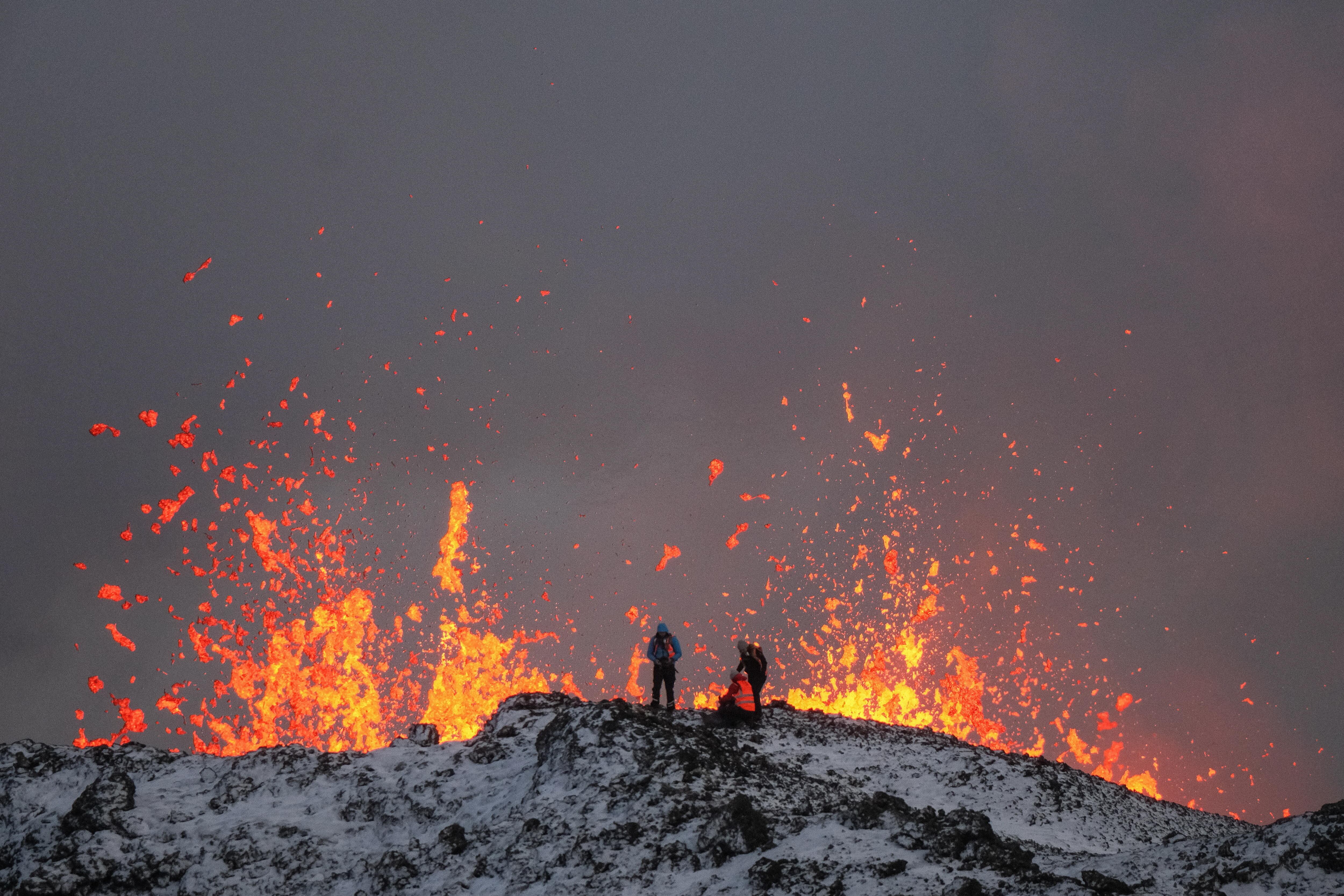 -FOTODELDÍA- EA2876. GRINDAVIK (ISLANDIA), 19/12/2023.- Un equipo de científicos trabaja hoy, en la cresta de una fisura volcánica mientras sale lava durante una erupción volcánica, cerca de la ciudad de Grindavik, en la península de Reykjanes (Islandia). La Oficina Meteorológica de Islandia (OMI) anunció el inicio de una erupción volcánica fisural cerca del cráter de Sundhnuka, al noreste de Grindavik, en la noche del 18 de diciembre, tras semanas de intensa actividad sísmica en la zona. La potencia y la actividad sísmica de la erupción han disminuido con el tiempo, informó la OMI el 19 de diciembre, añadiendo que se han registrado unos 320 seísmos desde el inicio de la erupción. EFE/EPA/ANTON BRINK