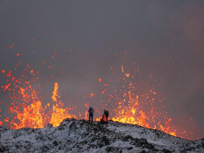 -FOTODELDÍA- EA2876. GRINDAVIK (ISLANDIA), 19/12/2023.- Un equipo de científicos trabaja hoy, en la cresta de una fisura volcánica mientras sale lava durante una erupción volcánica, cerca de la ciudad de Grindavik, en la península de Reykjanes (Islandia). La Oficina Meteorológica de Islandia (OMI) anunció el inicio de una erupción volcánica fisural cerca del cráter de Sundhnuka, al noreste de Grindavik, en la noche del 18 de diciembre, tras semanas de intensa actividad sísmica en la zona. La potencia y la actividad sísmica de la erupción han disminuido con el tiempo, informó la OMI el 19 de diciembre, añadiendo que se han registrado unos 320 seísmos desde el inicio de la erupción. EFE/EPA/ANTON BRINK