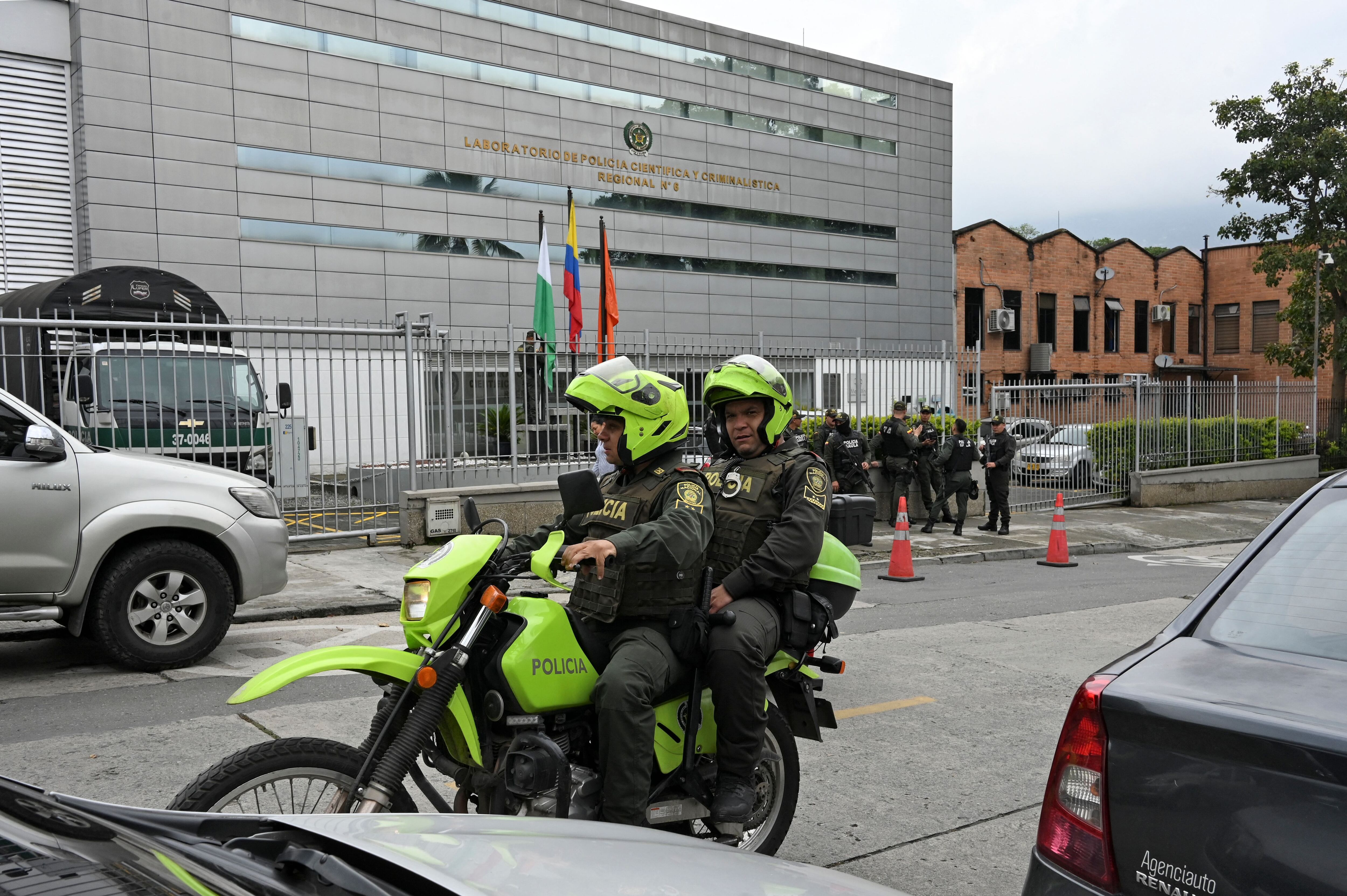 Oficiales de policía pasan en una motocicleta mientras otros montan guardia en Medellín. Vía Getty Images