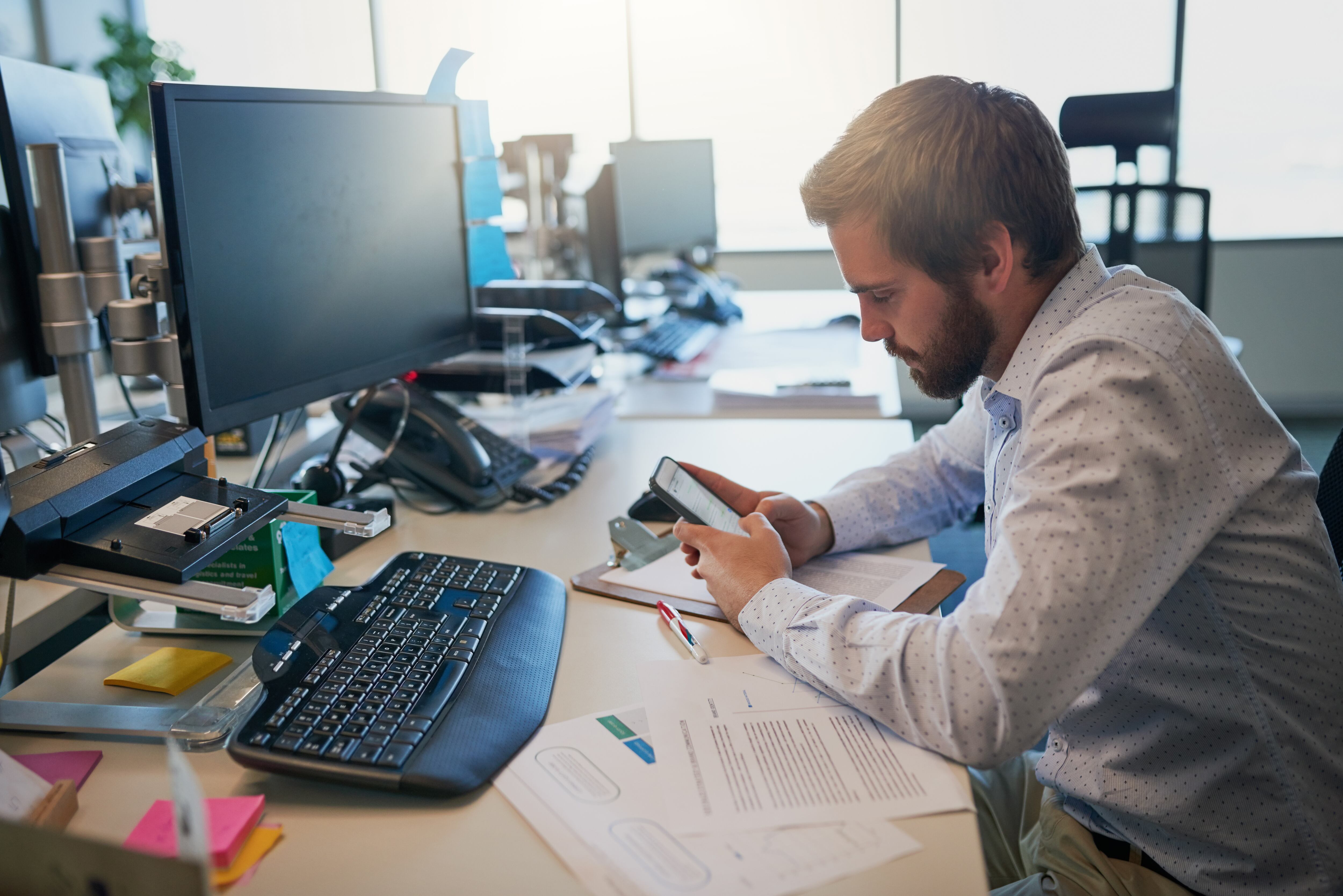 Shot of a focused young businessman texting on his cellphone while being seated behind his desk in the office