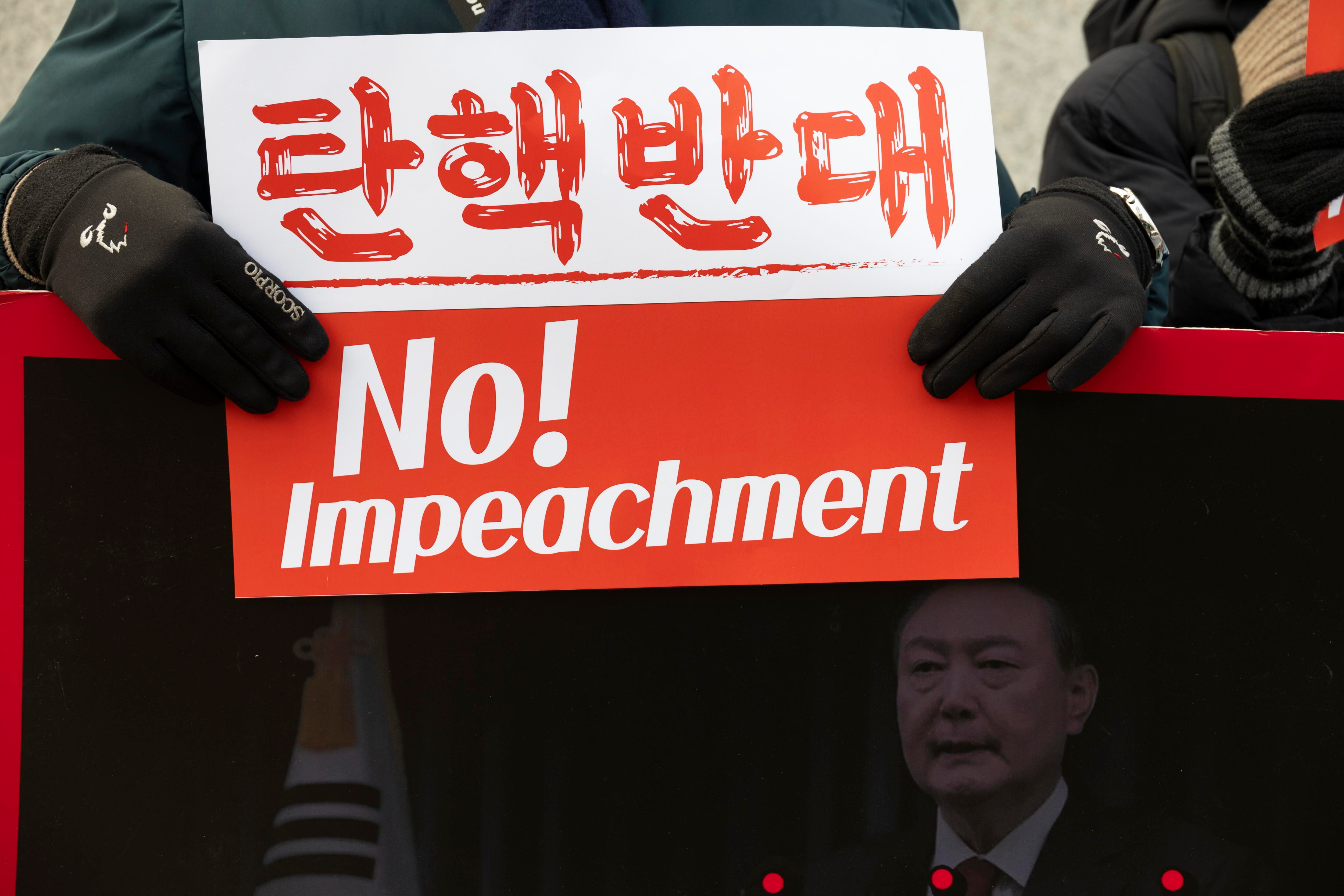 Seúl (República de Corea), 14/01/2025.- Un partidario del presidente surcoreano, Yoon Suk-yeol, sostiene una pancarta durante una concentración cerca del Tribunal Constitucional.