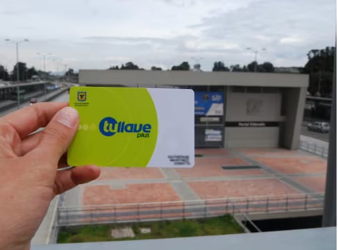 Tarjeta TuLlave Plus personalizada y al fondo una estación de Transmilenio. (Foto: Colprensa).
