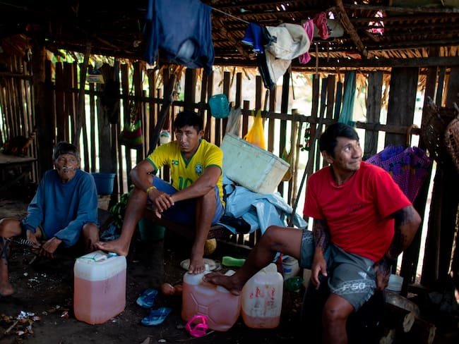 Arara indigenous men sit next jerry cans with petrol at the Laranjal tribal camp, in Arara indigenous land, Para state, in the northern Brazilian Amazon rainforest, on March 15, 2019. - Isolated and off the grid, the nearly 200 residents of Laranjal village on the edge of the Iriri River in Brazil&#039;s northern state of Para are among the some 800,000 indigenous people President Jair Bolsonaro says he wants to &quot;integrate into society.&quot;Bolsonaro&#039;s remarks alarmed the Arara, who like other indigenous groups across Latin America&#039;s biggest country have long battled to protect their traditional way of life, away from towns and cities. (Photo by Mauro Pimentel / AFP)        (Photo credit should read MAURO PIMENTEL/AFP via Getty Images)