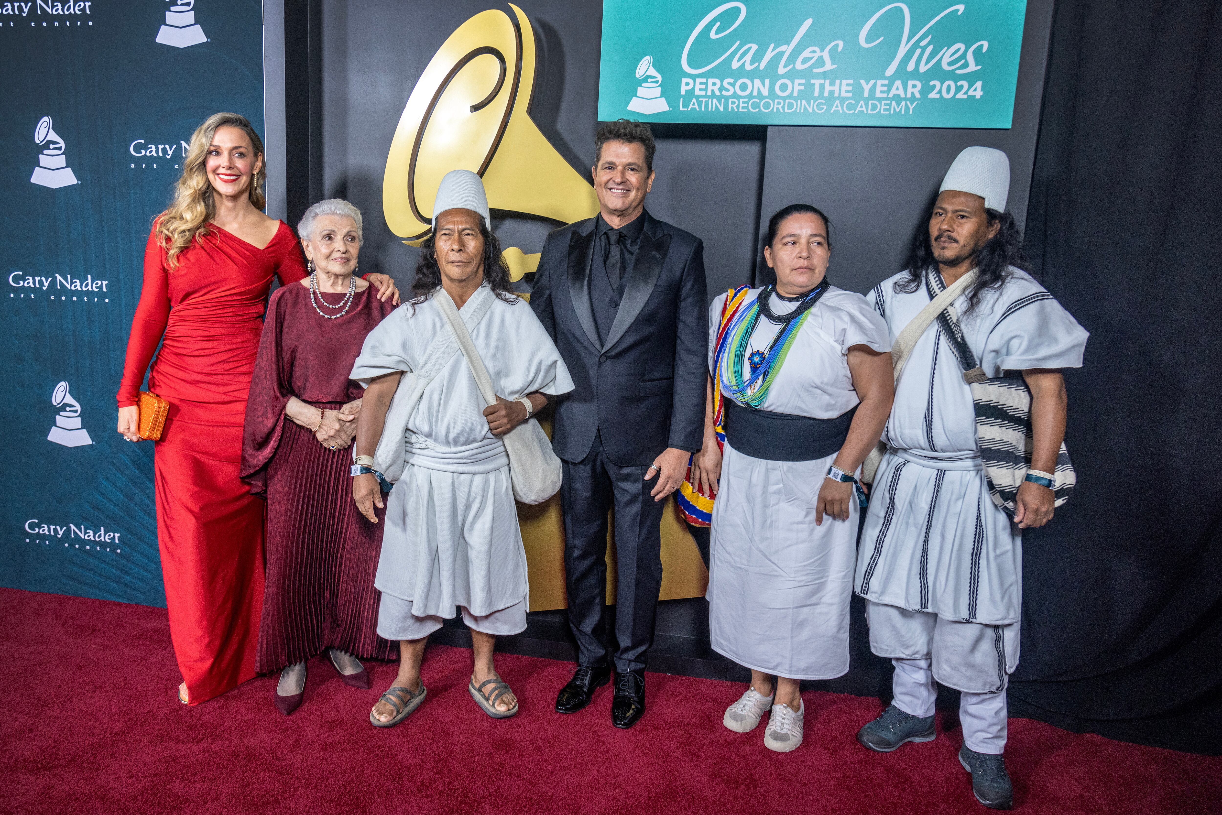 Miami Beach (United States), 14/11/2024.- Colombian singer Carlos Vives (C) Vives' wife Claudia Elena, (L), Vives' mother Aracelly (2-L) and the traditional band Indios Arhuacos, attend the red carpet at the Latin Grammy Person of the Year event. EFE/EPA/CRISTOBAL HERRERA-ULASHKEVICH