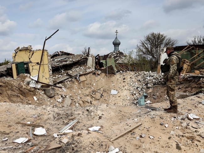 A Ukranian serviceman looks into a crater and a destroyed home are pictured in the village of Yatskivka, eastern Ukraine on April 16, 2022. - Russia&#039;s military focus now seems to be on seizing the eastern Donbas region, where Russian-backed separatists control the Donetsk and Lugansk areas. Lugansk governor Serhiy Gaidai called on April 16, 2022, for civilians to leave the area while they still can. (Photo by RONALDO SCHEMIDT / AFP) (Photo by RONALDO SCHEMIDT/AFP via Getty Images)
