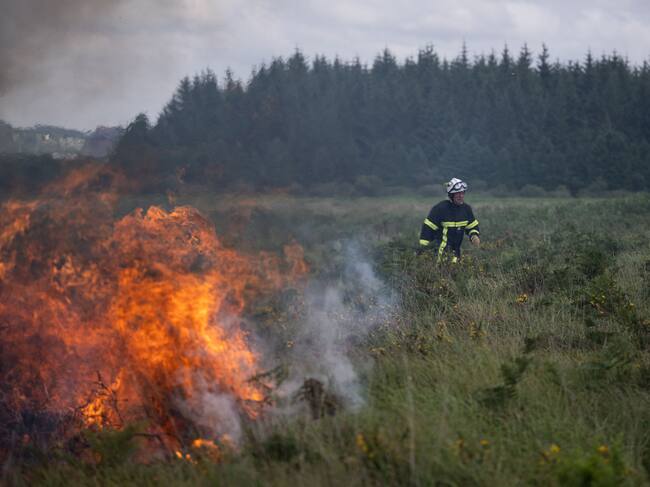 Los bomberos rocían agua sobre un incendio forestal que arrasa Monts d'Arree, cerca de Brasparts, Bretaña, el 19 de julio de 2022. (Photo by LOIC VENANCE / AFP) (Photo by LOIC VENANCE/AFP via Getty Images)