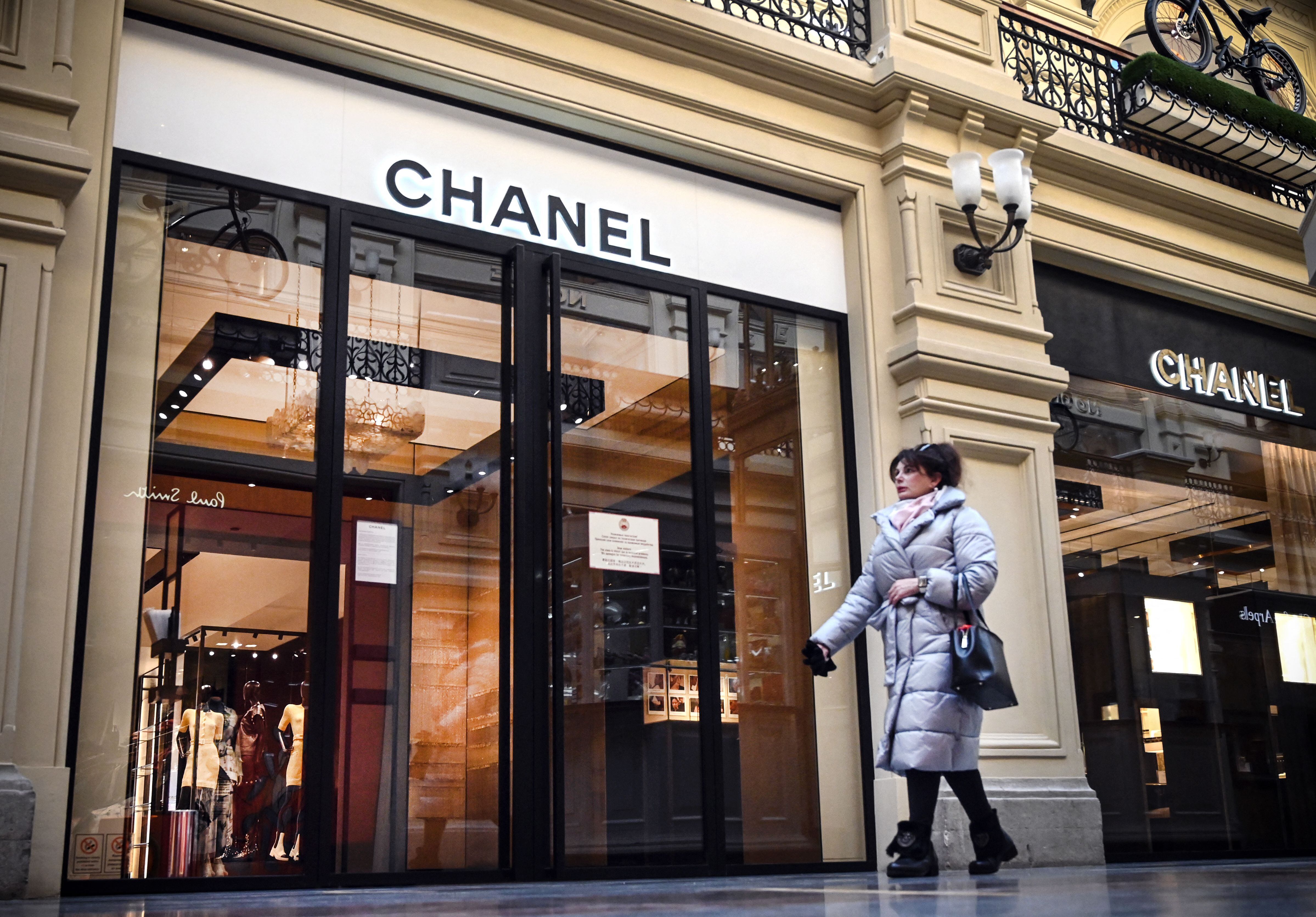 A woman walks past a closed Chanel shop in Moscow on March 10, 2022. - Many fashion and luxury brands have also announced the interruption of their activities in Russia, including Chanel, Hermes, Prada and LVMH. Luxury has been exempted from sanctions, but many groups have taken the decision to close their shops in the country. (Photo by AFP) (Photo by -/AFP via Getty Images)