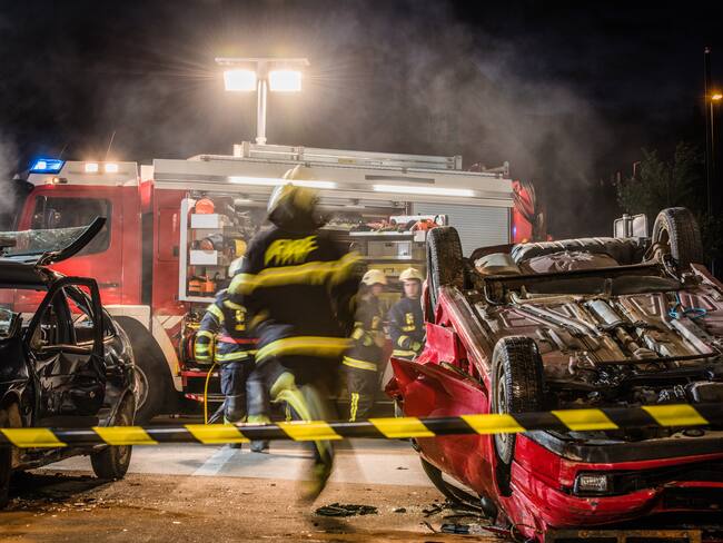 Night shot of a firefighters working on serious traffic accident scene with upside down car, fire engine in background.