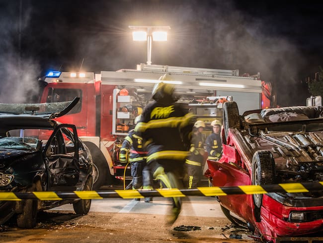 Night shot of a firefighters working on serious traffic accident scene with upside down car, fire engine in background.