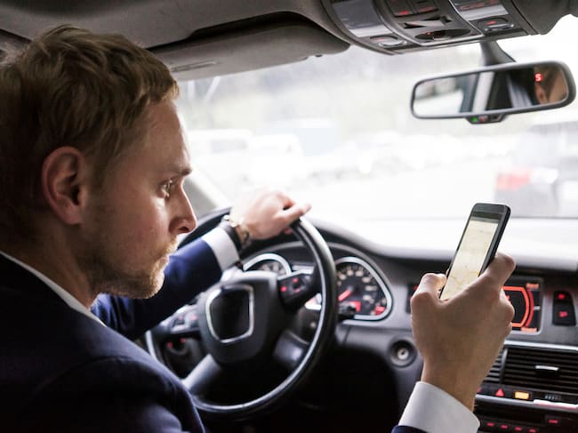 Hombre usando el celular mientras conduce. Foto: Getty Images.