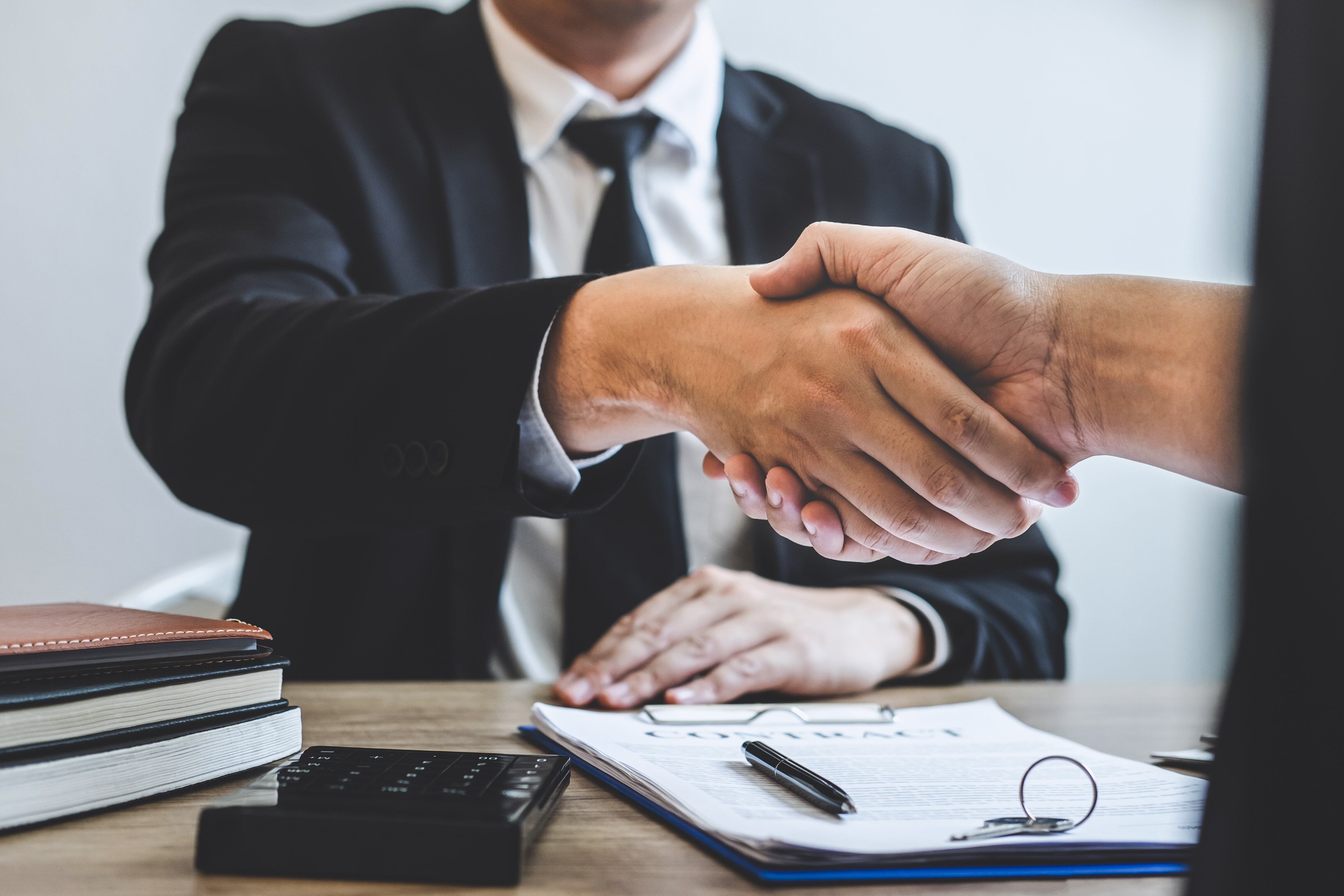 Finishing to successful deal of real estate, Broker and client shaking hands after signing contract approved application form, concerning mortgage loan offer for and house insurance.